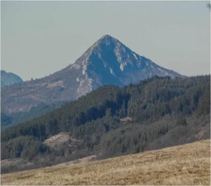 Pyramid-shaped summit above wooded hills